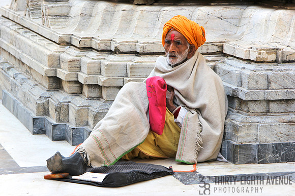 Old Man With Orange Turban Sitting at Monument
