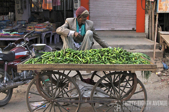 Old Man Selling Green Peppers On Cart